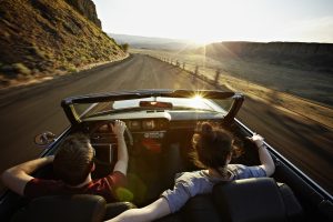 young-couple-driving-convertible-at-sunset